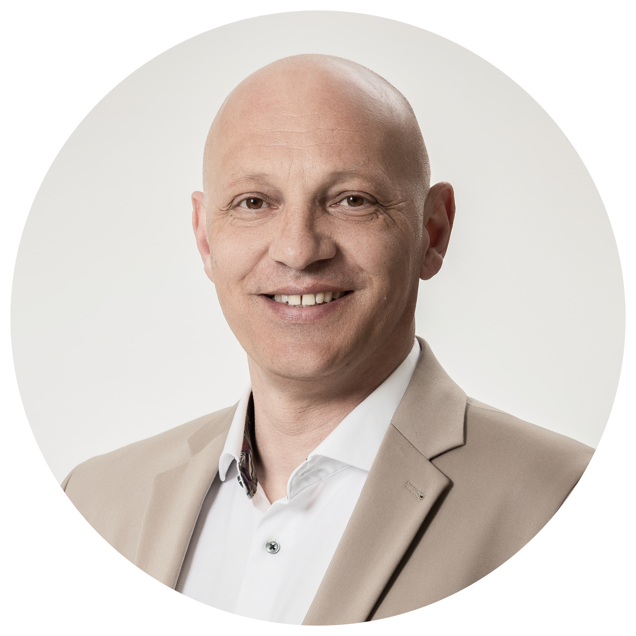 Ein Mann mit Glatze trägt einen beigen Anzug und wirkt neutral vor hellem Hintergrund