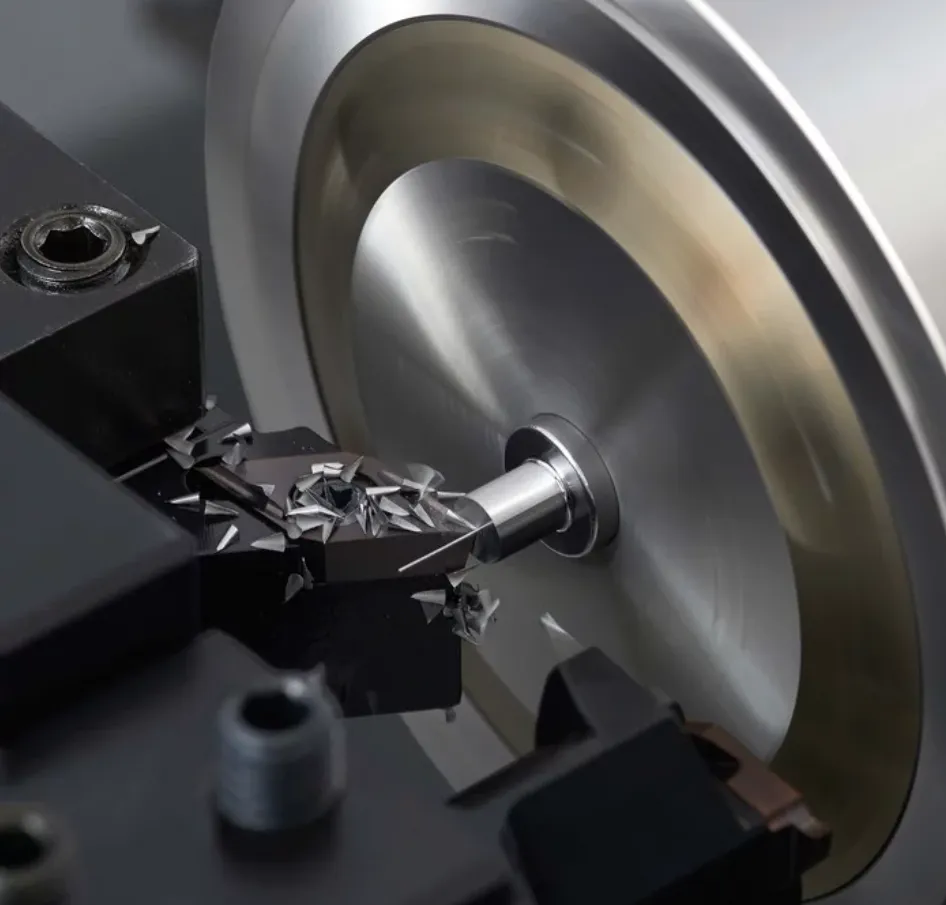 Ein silberner Metallzylinder wird an einer Drehmaschine mit schwarzem Werkzeug bearbeitet